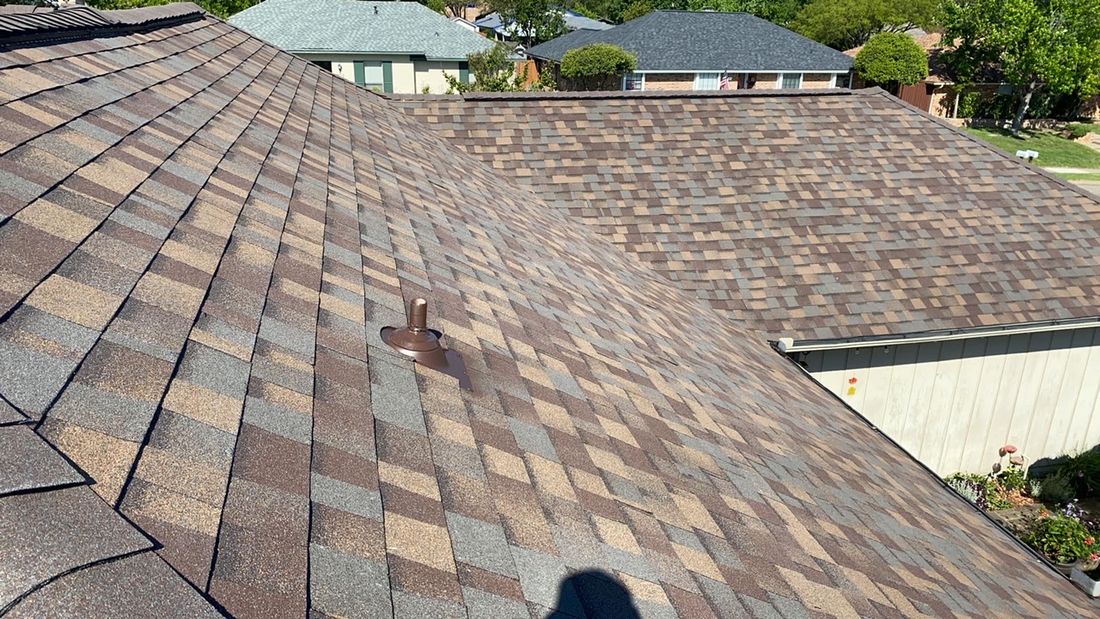 Finished shingle roof with a vent boot and gutter line.